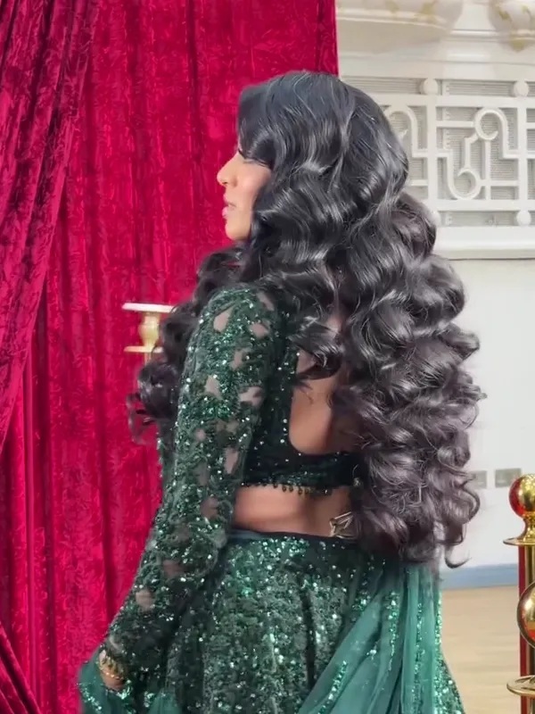 Back view of voluminous Old Hollywood barrel curls worn loose with a green sequin lehenga