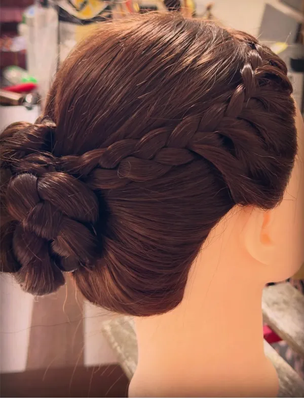 Back view of Dutch crown braid meeting a braided low bun on a mannequin head