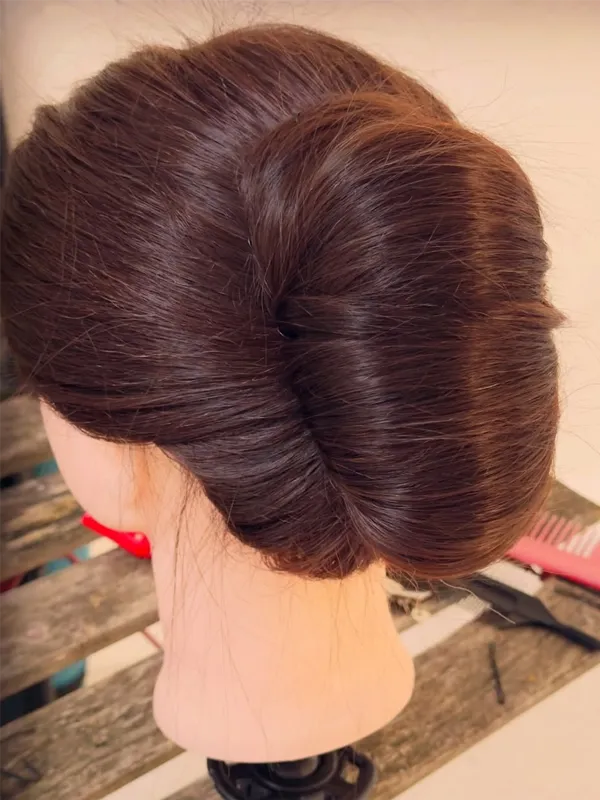 Back view of a sleek twisted chignon updo on a mannequin head
