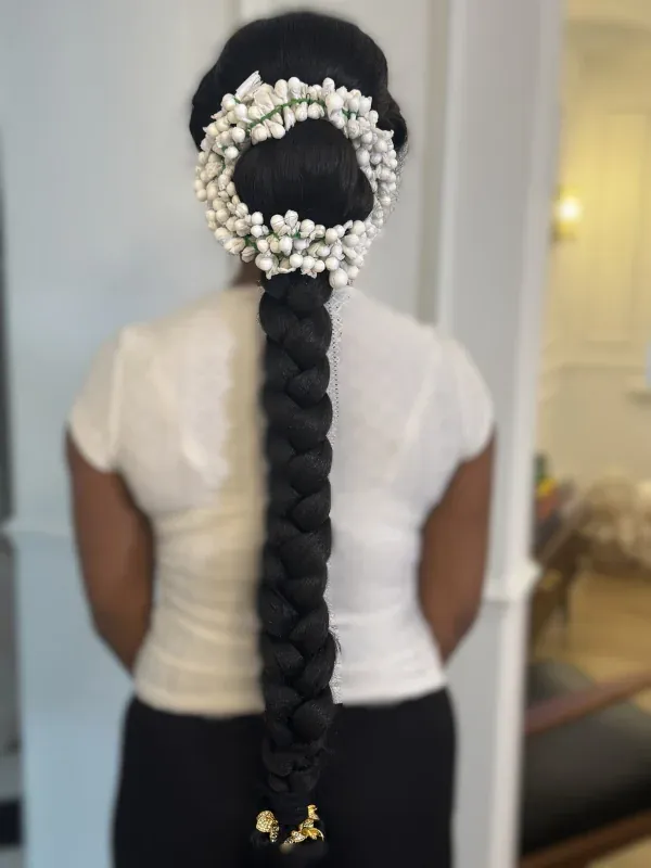 Back view of a long thick rope braid adorned with a white jasmine flower garland