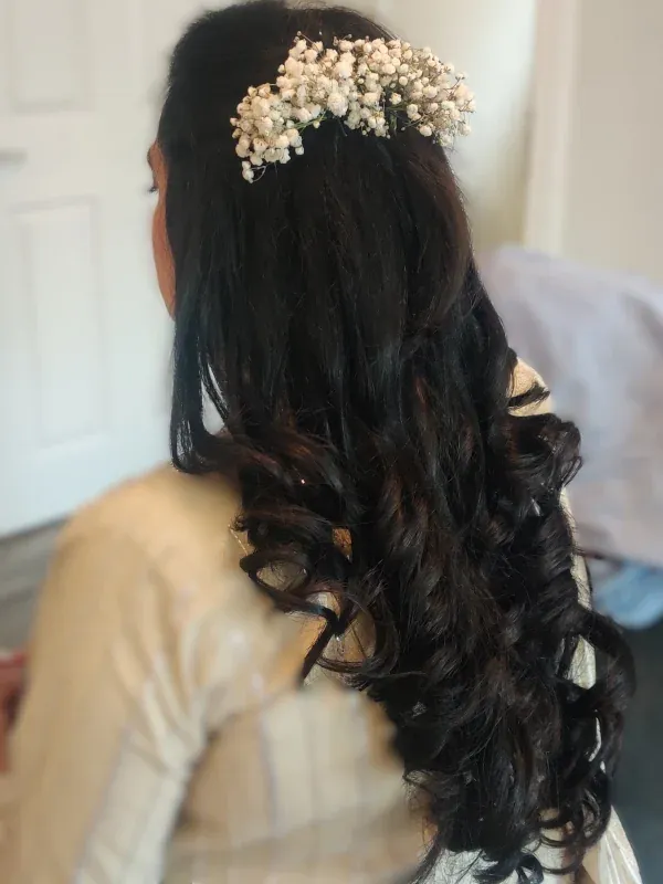 Back view of a half-up half-down style with loose curls and a baby's breath hair piece
